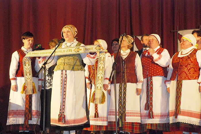 Folkloro ansamblis „Savingė“ jubiliejaus proga padovanojo tautinę juostą su užrašu „Gelvonų vidurinei mokyklai 235“.