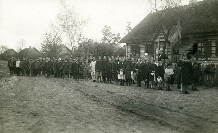 Kernavė nuo seno domino ekskursantus. Vienu pirmųjų ir garsiausių galima būtų laikyti Liudviką Kondratovičių (Vladislovą Sirokomlę), kuris 19 a. viduryje dalyvavo Vilniaus archeologijos komisijos veikloje, lankėsi Kernavėje ir Čiobiškyje, kasinėjo piliakalnius ir pilkapius, ieškojo archeologijos radinių, tai aprašė.   Kernave labiau imta domėtis atkūrus Lietuvos nepriklausomybę, tvirtėjant tautiškumo idėjoms. Palei demarkacijos liniją atsidūrusi senoji Lietuvos sostinė tapo savotišku traukos centru pilietinėje kovoje dėl atplėšto Vilniaus krašto, čia lankydavosi patriotiškai nusiteikęs jaunimas. Šioje nuotraukoje užfiksuota viena ankstyvųjų ekskursijų į Kernhavę. Prie senojo pradžios mokyklos pastato - Musninkų valsčiaus mokiniai su mokytojais. Priekyje stovintis berniukas laiko Lietuvos valstybinę vėliavą. Nuotrauka daryta 1924 metais (Iš Ukmergės kraštotyros muziejaus fondo. limis.lt).