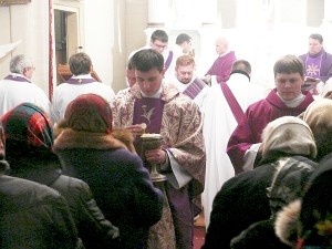 Kunigas Tadas Piktelis parapijiečiams dalija Komuniją.
